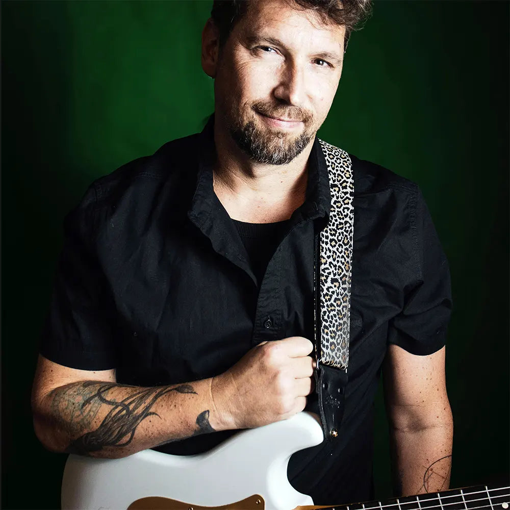 Gitarrist mit weißer E-Gitarre und stilvollem Leopardenmuster-Gitarrengurt, hochwertiger Premium-Gitarrengurt für Musiker.