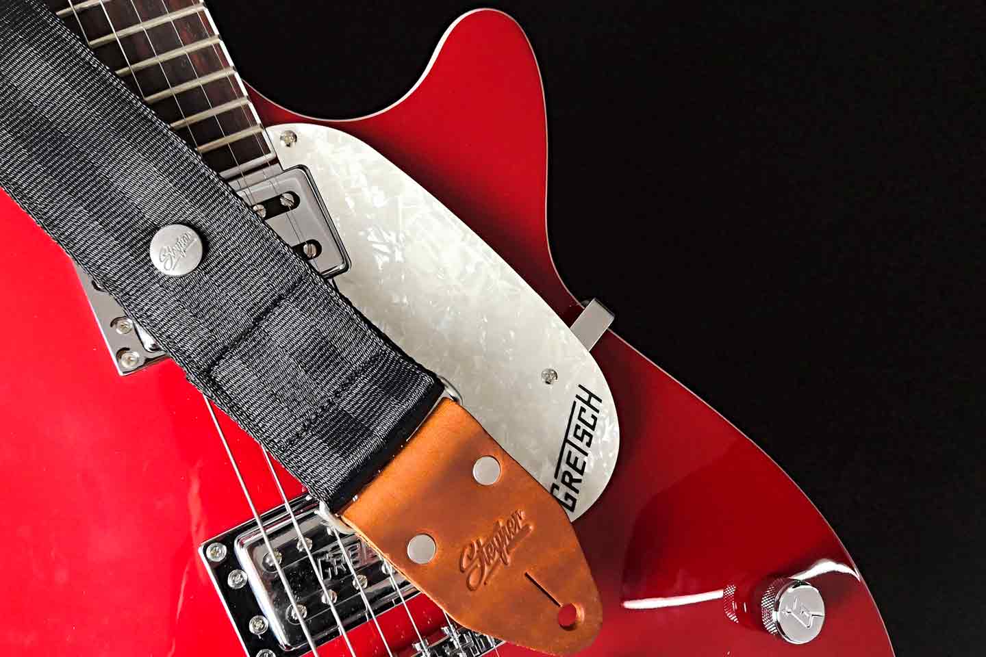 Schwarzer Gitarrengurt aus Autogurt auf einer roten Gitarre rutschfest