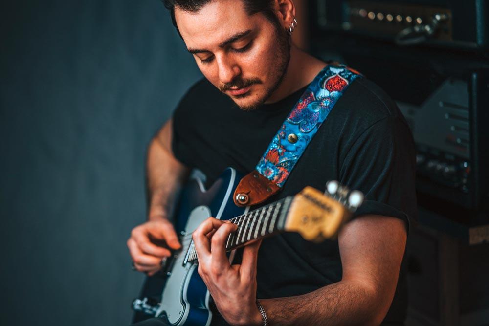 Designer Gitarrengurt blau mit Blumen Muster und Schimmer Effekt an einer blauen Fender Telecaster mit dem Gitarrist Marco Bozzo