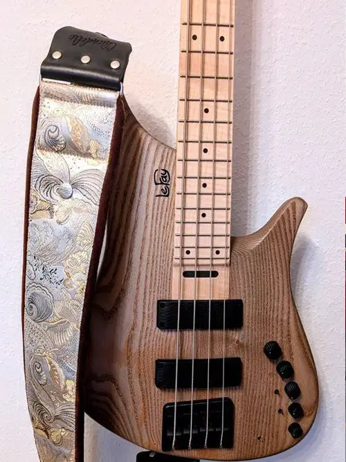 Gepolsterter Bassgurt in Silber und Gold mit Blumenmuster und schwarzer Lederlasche an einem Lefay-Bass in Holzoptik