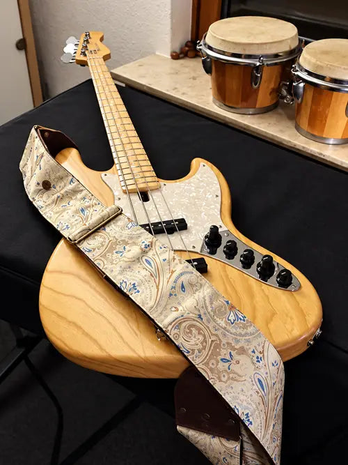 Beiger Paisley-Bassgurt im Deluxe-Modell an einem E-Bass in Naturholz mit perlweißem Schlagbrett
