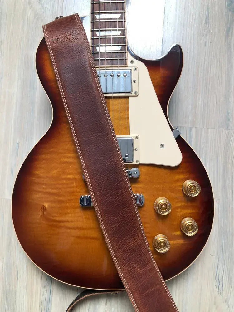 Brauner Steyner Leder Gitarrengurt mit Polsterung und Ziernähten auf einer Les Paul Gitarre in Sunburst.