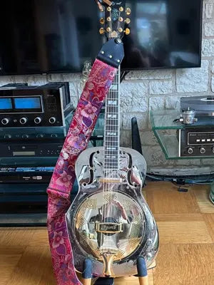 Resonatorgitarre mit Metallkorpus und extra breitem Steyner-Gitarrengurt in rot-pinkem Blumenmuster.