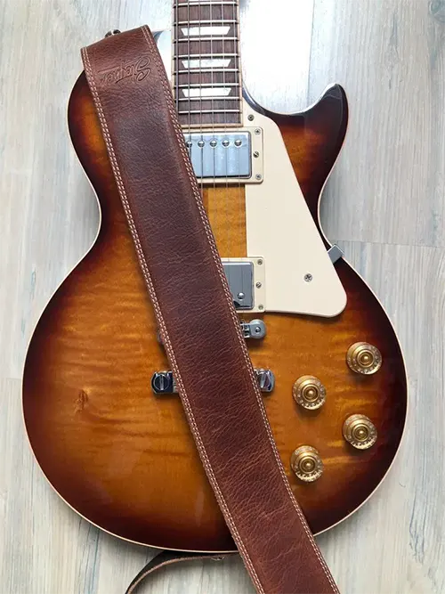 Brauner Vintage Leder Gitarrengurt mit heller Naht auf einer Sunburst Gibson Les Paul