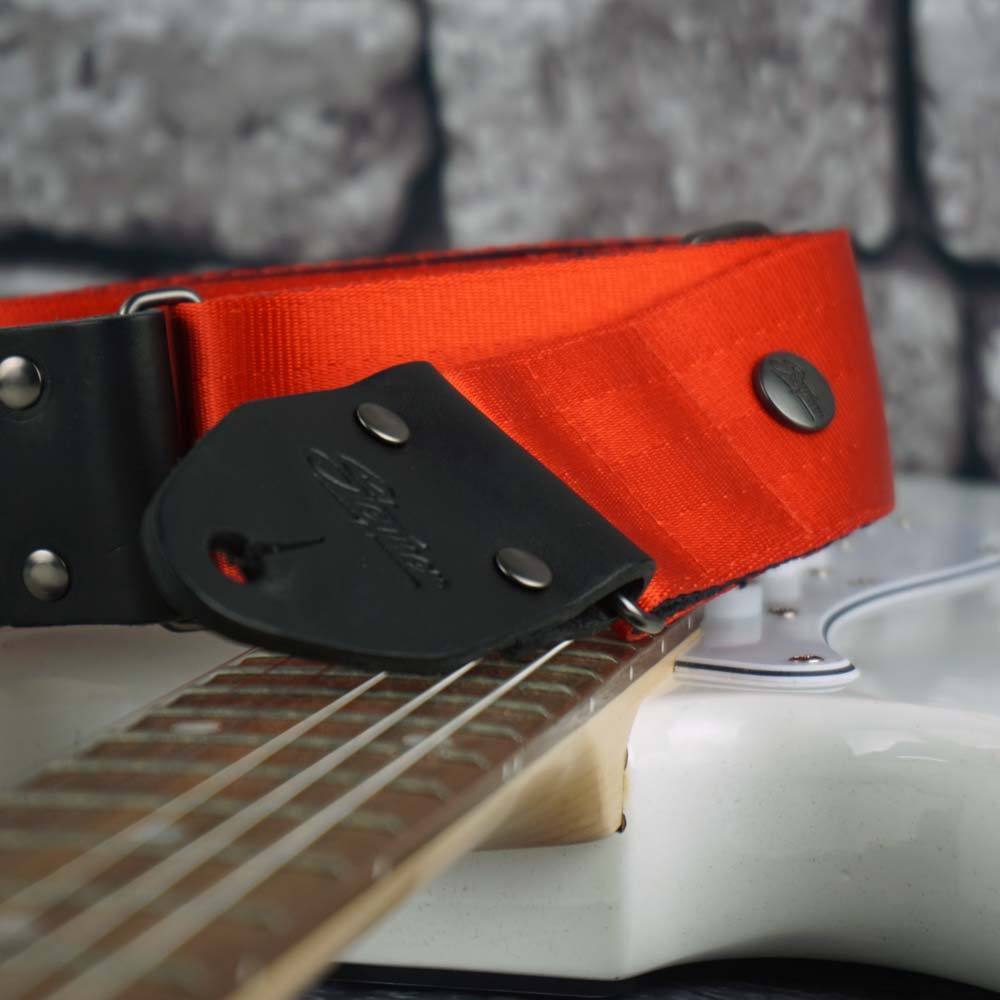 Hochwertiger Gitarrengurt aus rotem Sicherheitsgurtband auf einer weißen Gitarre