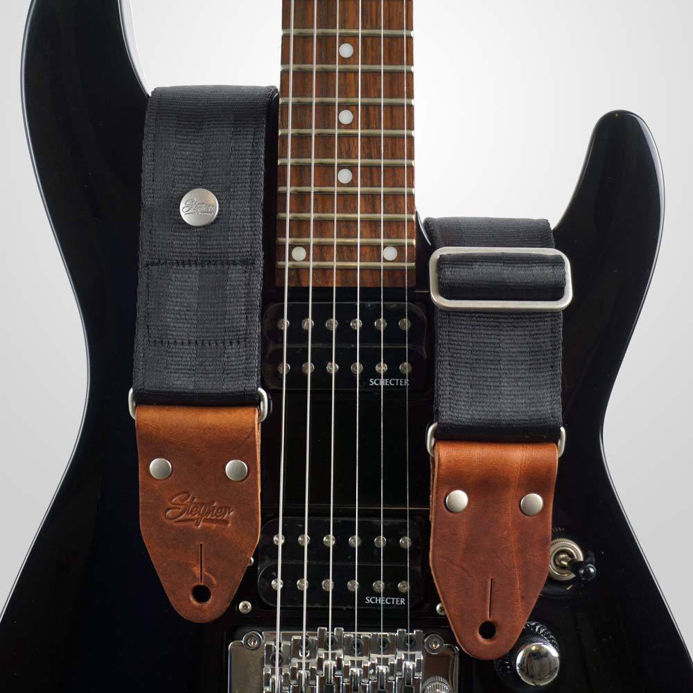 Gitarrengurt schwarz aus Autogurt - Sicherheitsgurt auf einer schwarzen Gitarre