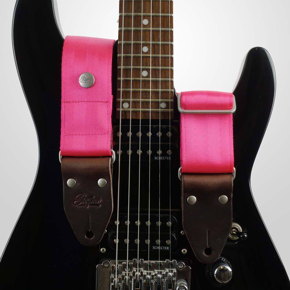 sicherheitsgurt gitarrengurt pink auf schwarzer Gitarre