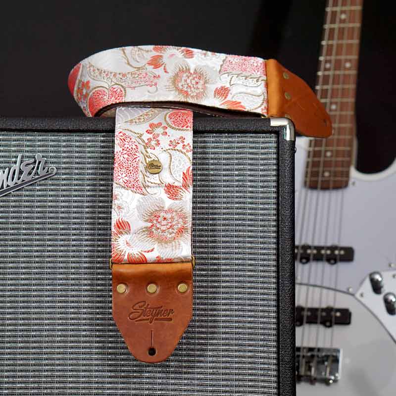 8 cm breiter weisser Bassgurt mit buntem Blumen Muster auf Fender Amp mit E Bass Gitarre