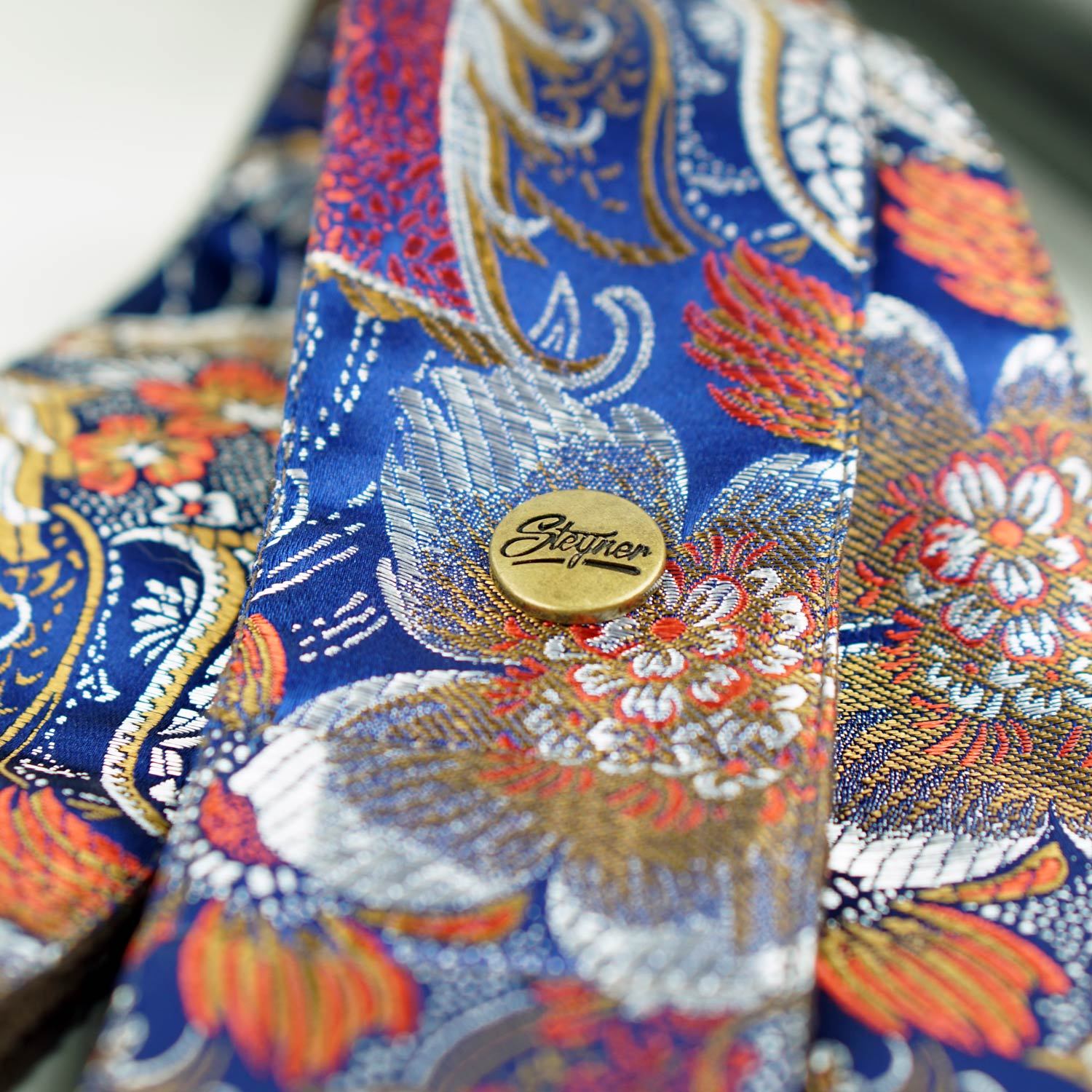 Blauer Gitarrengurt mit Blumen Muster in bunt -  in der Mitte eine Niete mit Marken Logo Steyner - bestickt