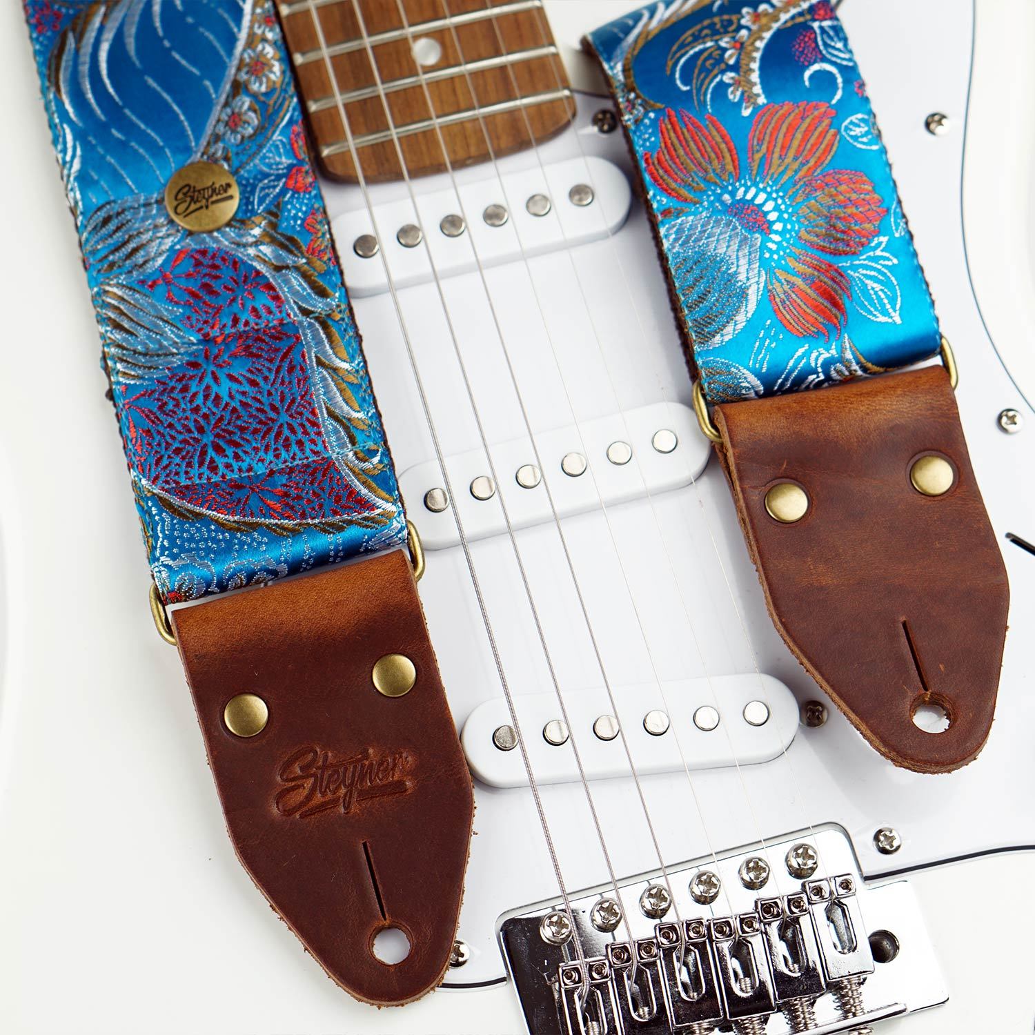 Bunter Gitarrengurt blau im Vintage Stil mit Retro Blumen Muster auf einer weissen E-Gitarre