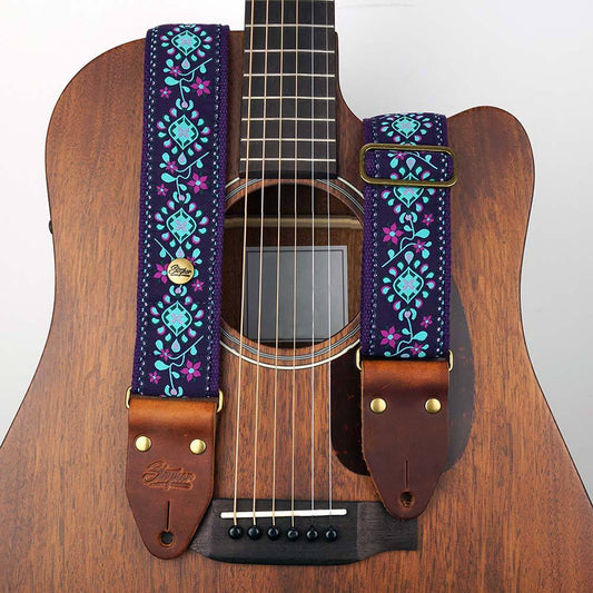 Steyner Retro Gitarrengurt mit floralem Muster in lila-türkis Tönen auf einer braunen Akustikgitarre